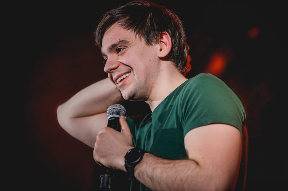 Sebastian Rejent na scenie z mikrofonem, uśmiechnięty